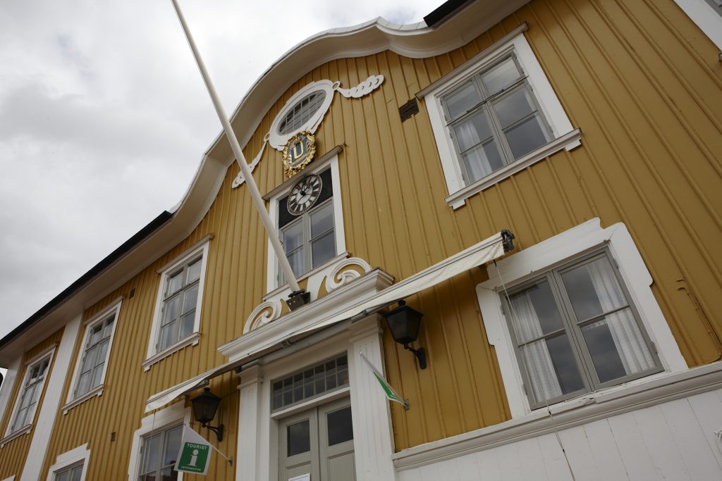 Bild på rådhuset i Ulricehamn. En gul träbyggnad med vita fönster.