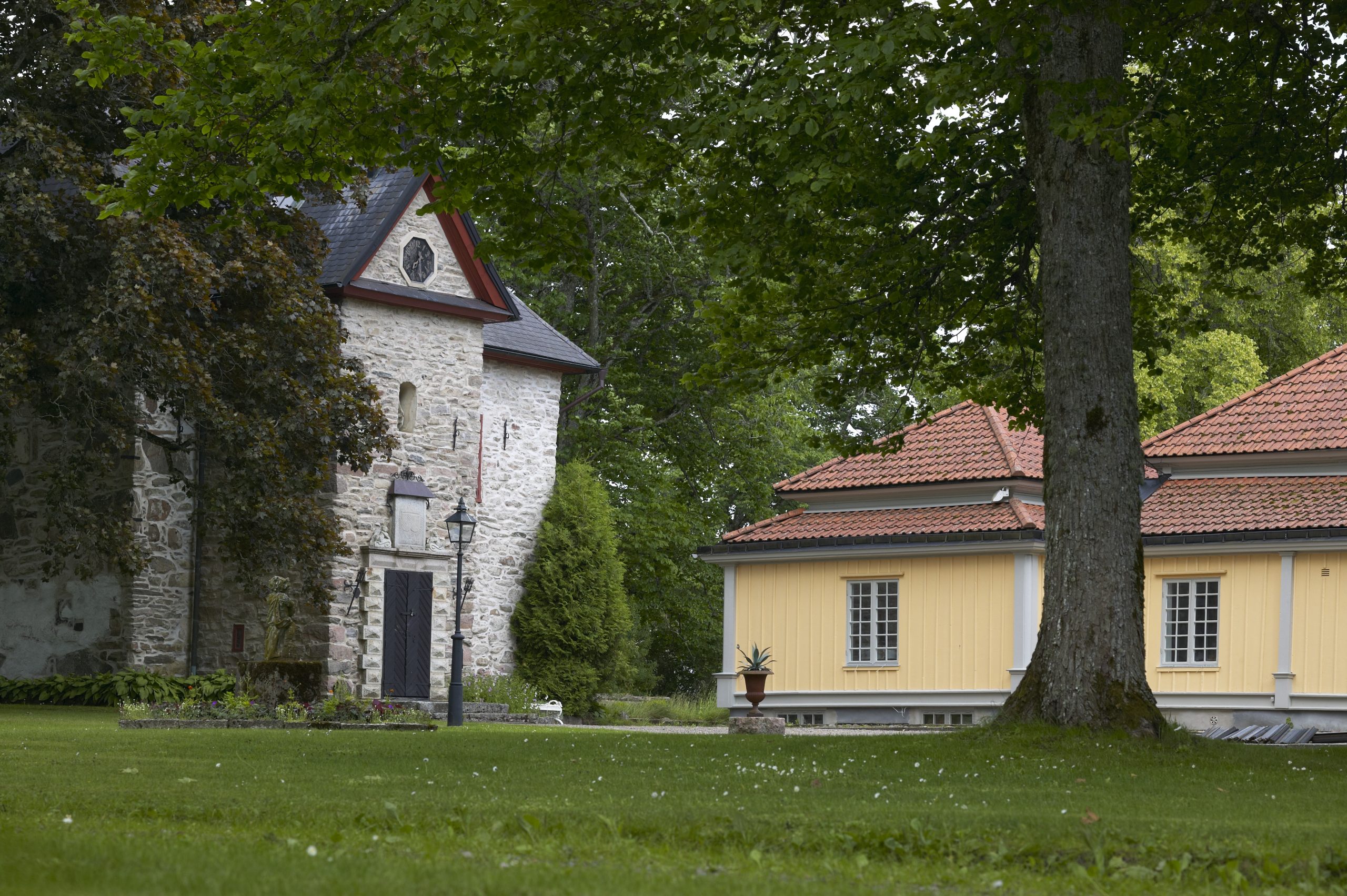 Bild på Vinsarp. En grå stenbyggnad och bredvid en ljusgul byggnad i puts med rött tegeltak.