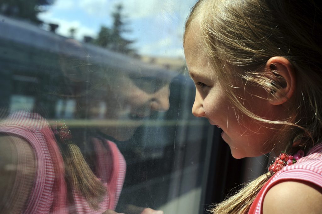 Bild på en flicka som tittar ut ur ett tågfönster.