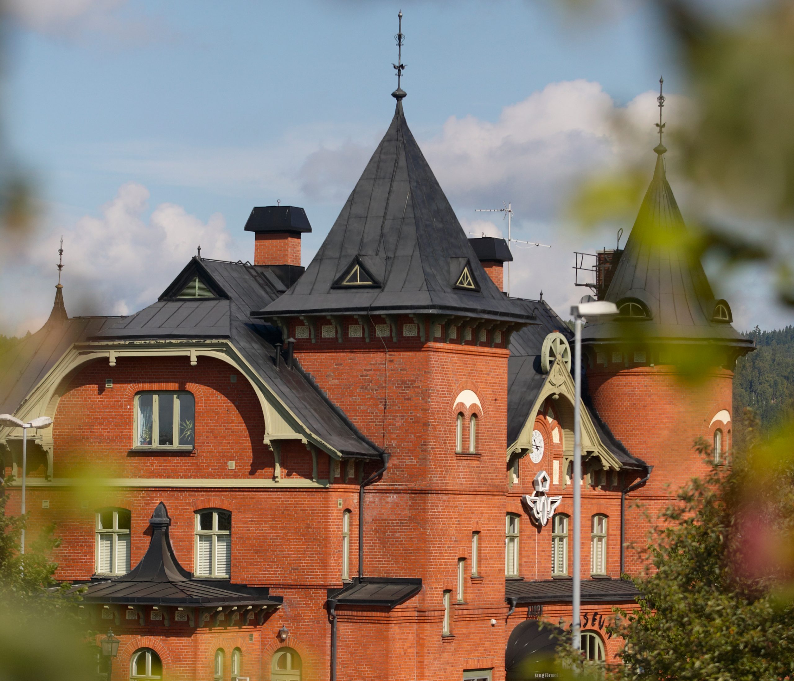 Bild på Stationshuset i Ulricehamn. En tegelbyggnad med två torn och svart tak.