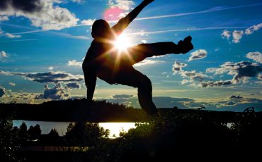 Bild på en kille som hoppar med himlen som bakgrund och solen i motljus.