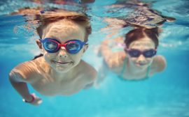 en flick och en pojke som simmar i en pool
