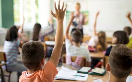 Bild på barn som räcker upp handen i ett klassrum