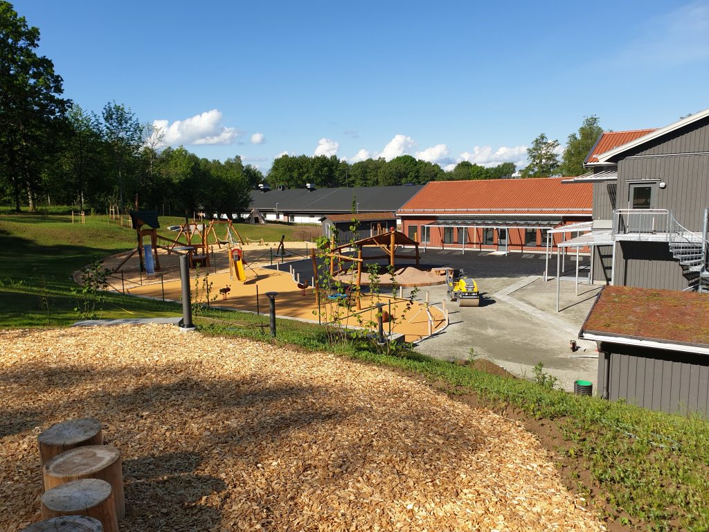 Bild på en utegård vid en förskola med olika lekredskap.