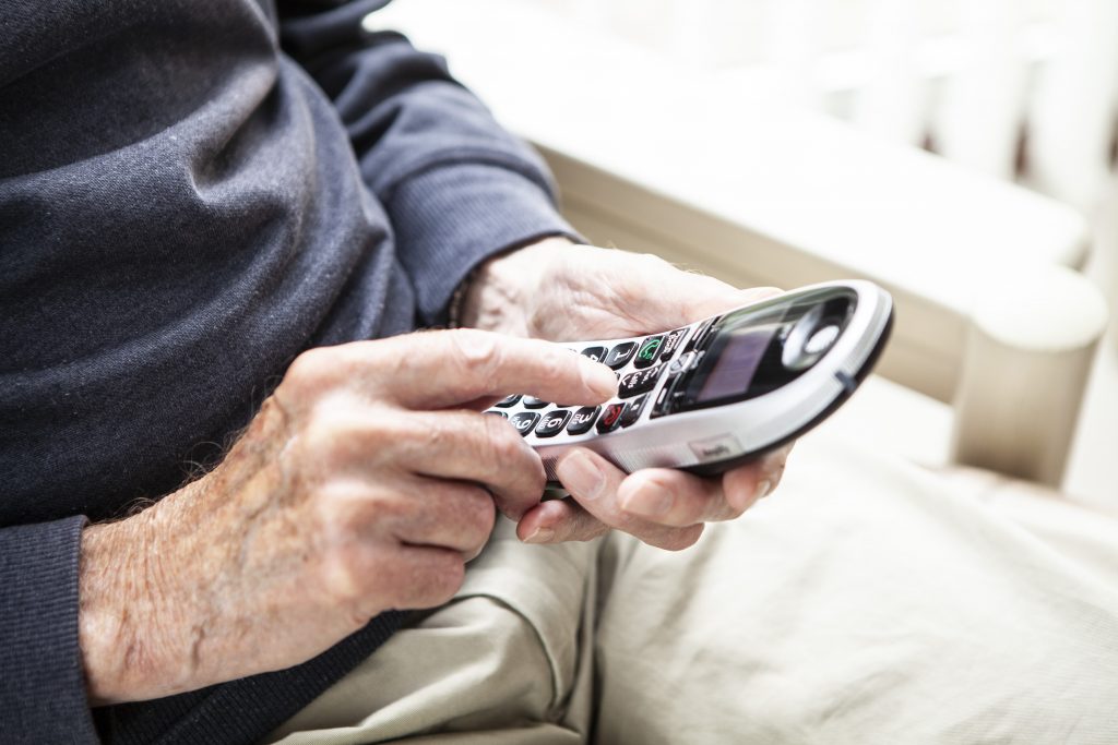 Äldre persons händer som håller i en mobiltelefon