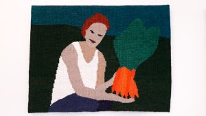 En bildväv av lin, väven föreställer en sittande kvinna som håller i ett knippe morötter.