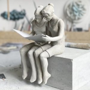 Två sittande skulpturer läser en tidning