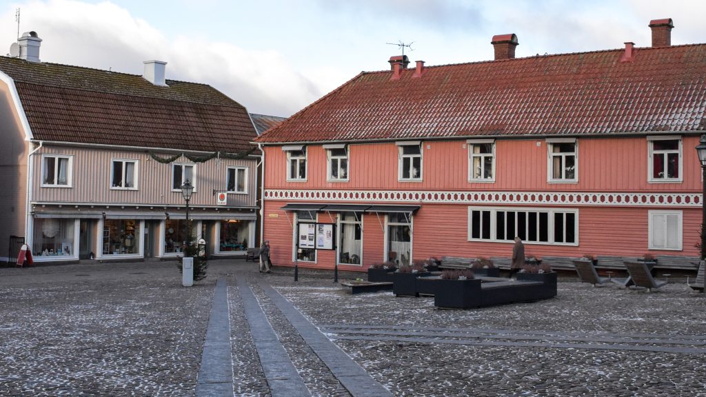 Två hus med träfasad vid torg med kullersten.